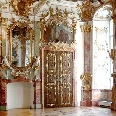 Prunkraum im Rokokostil in kräftigen Farben und Gold, mit kunstvoll verziertem Stuck, üppigen Malerei und Skulpturen