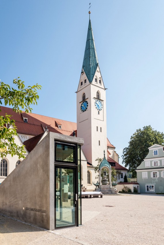 Eingansbereich zur Unterirdischen Erasmuskapelle auf dem St. Mang Platz, im Hintergrund die Kirche
