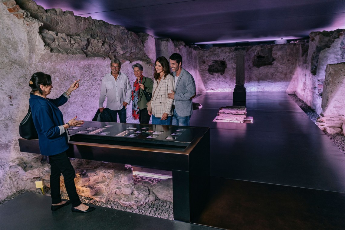 Gästeführerin mit Personengruppe im blau beleuchteten Schauraum Ersamuskapelle